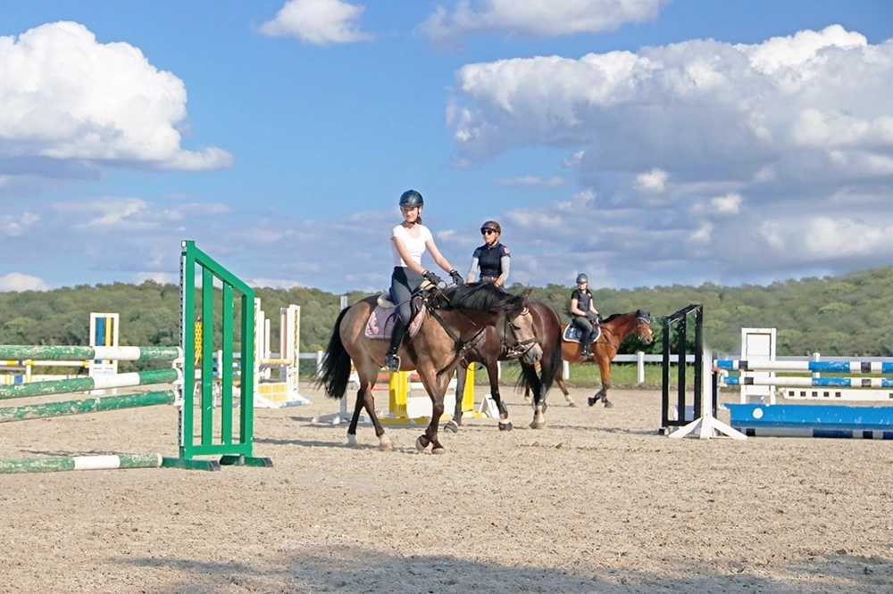 Kleine Gruppe von Reiterinnen auf Reitplatz zwischen Hindernissen