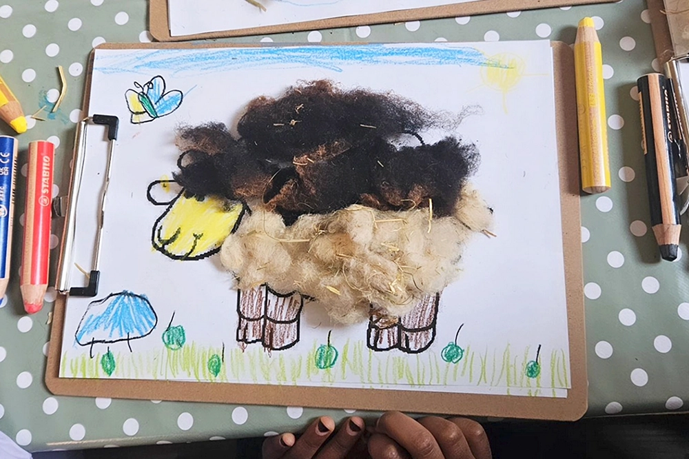 Kinderzeichnung eines Schafes mit Wolle beklebt