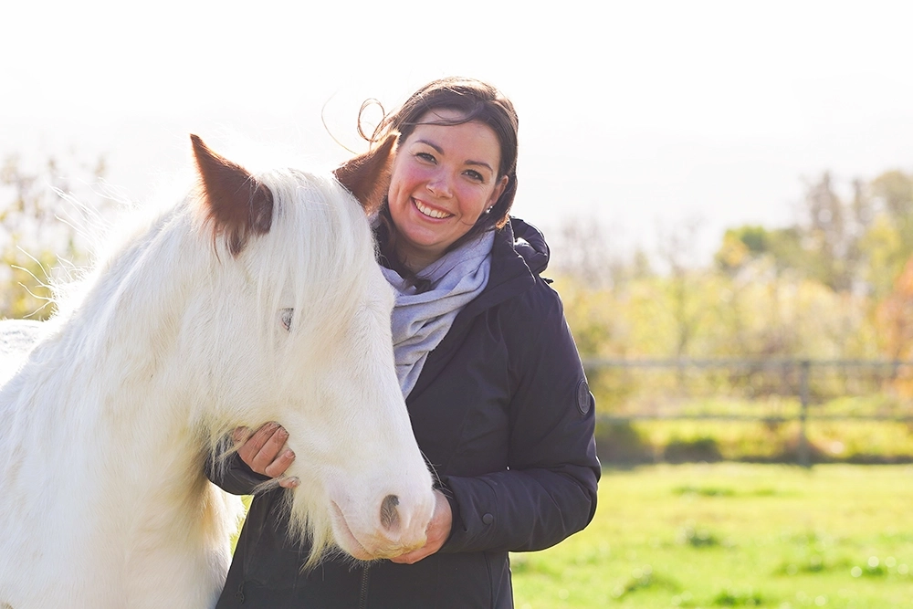 Christina Pavel steht neben weißem Ponny, streichelt Kopf
