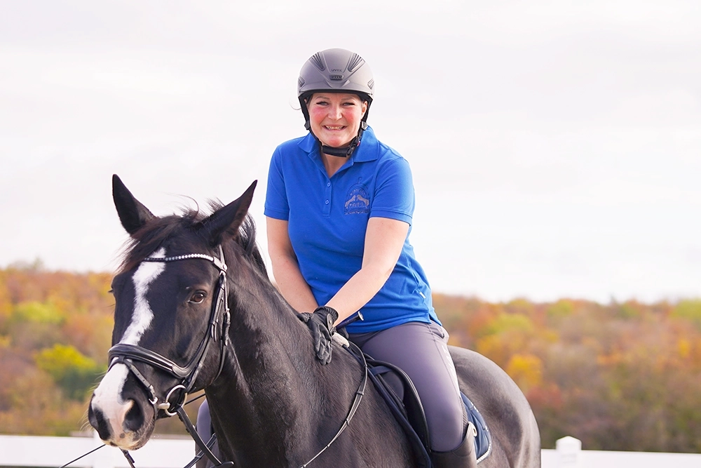 Lea auf schwarzbraunem Pferd, trägt Reithelm