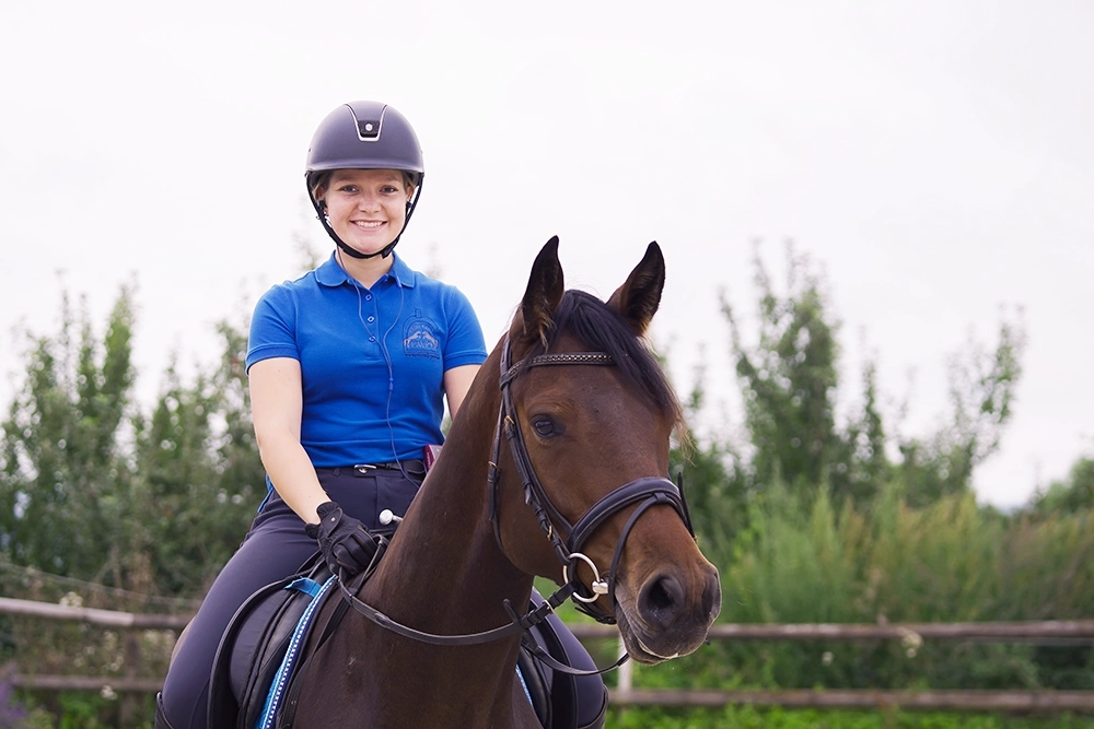 Dani auf braunem Pferd, trägt Reithelm