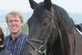 Peter Pavel steht neben dunkelbraunem Pferd