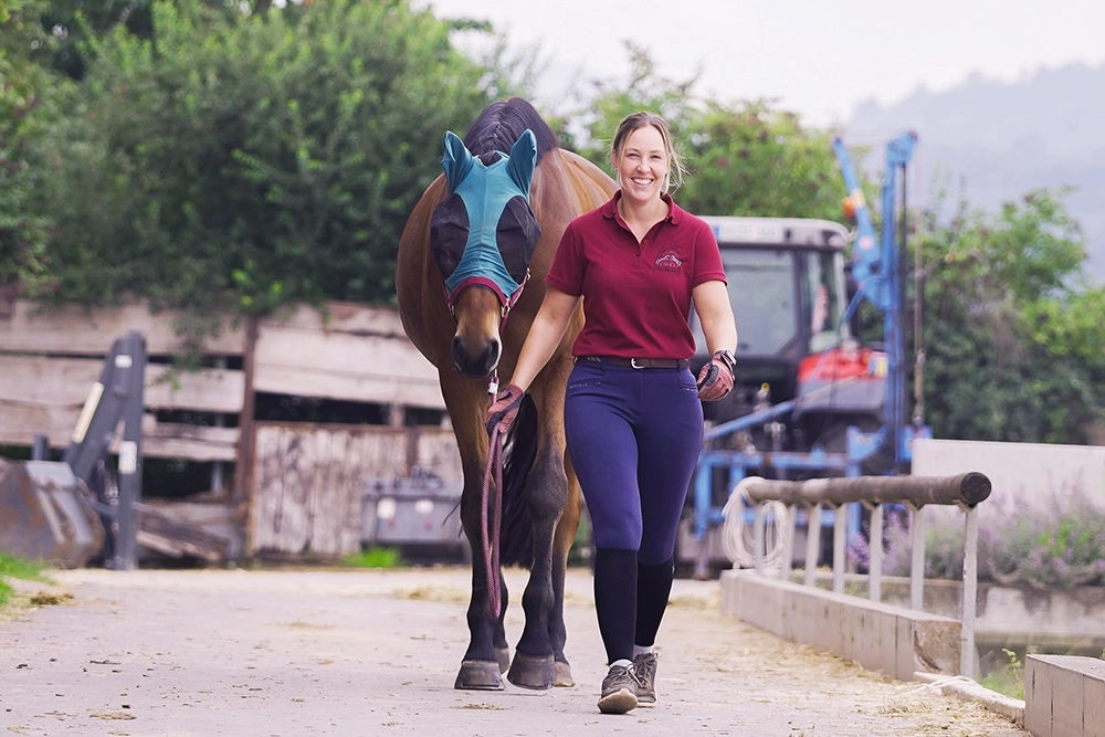 Sabrina führt braunes Pferd über den Hof