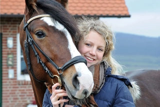 Viktoria steht neben braunem Pferd